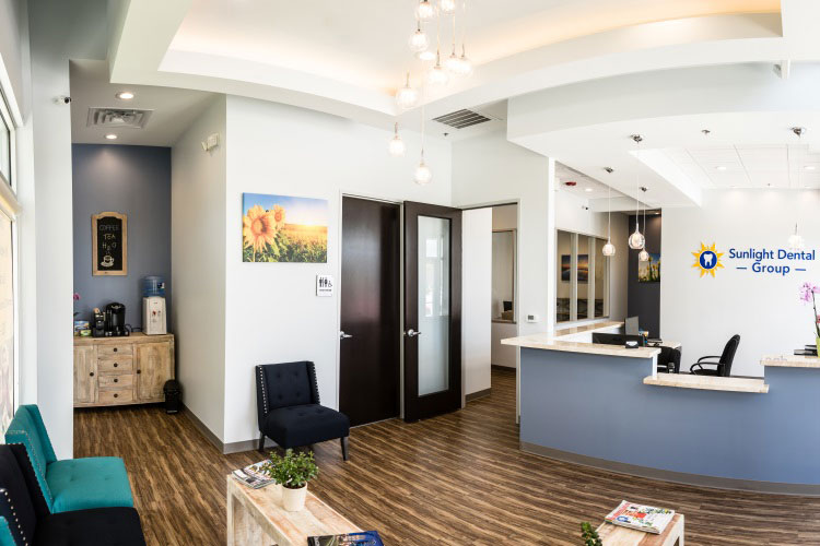 An image of a well-lit dental office interior with a reception area, waiting chairs, and a sign indicating the name of the practice.