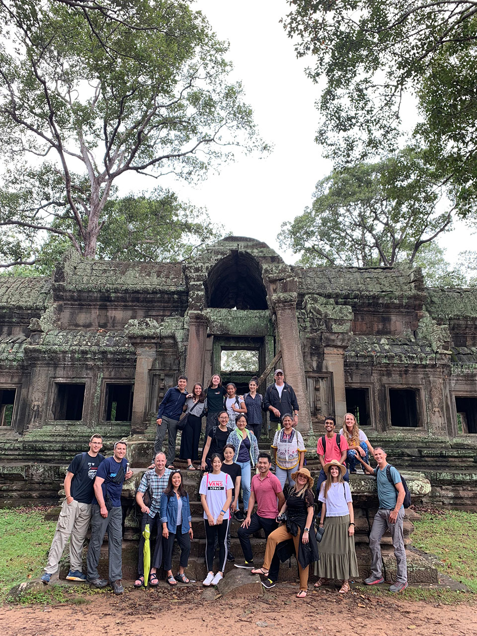 A group of people posing in front of a large, ornate temple with multiple levels and intricate architecture.