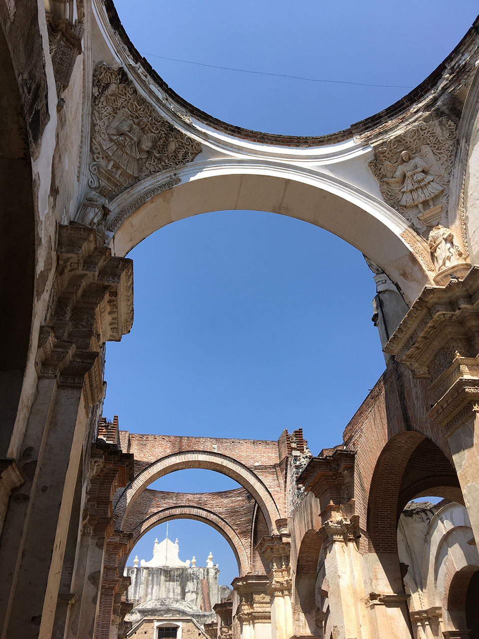 The image shows a large, arched stone structure with a high ceiling and a circular opening at the top. The interior is characterized by multiple rows of columns supporting the walls, and the architecture suggests historical significance.