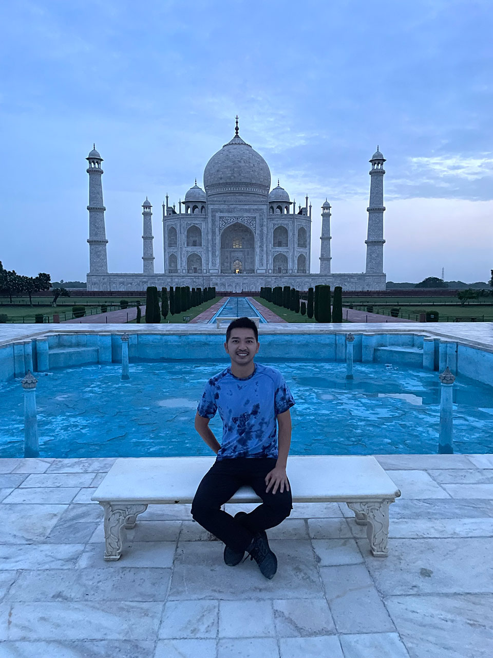 A person posing in front of the Taj Mahal, a renowned white marble mausoleum and UNESCO World Heritage Site.