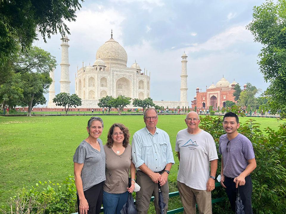 A group of people standing in front of the Taj Mahal, posing for a photo.