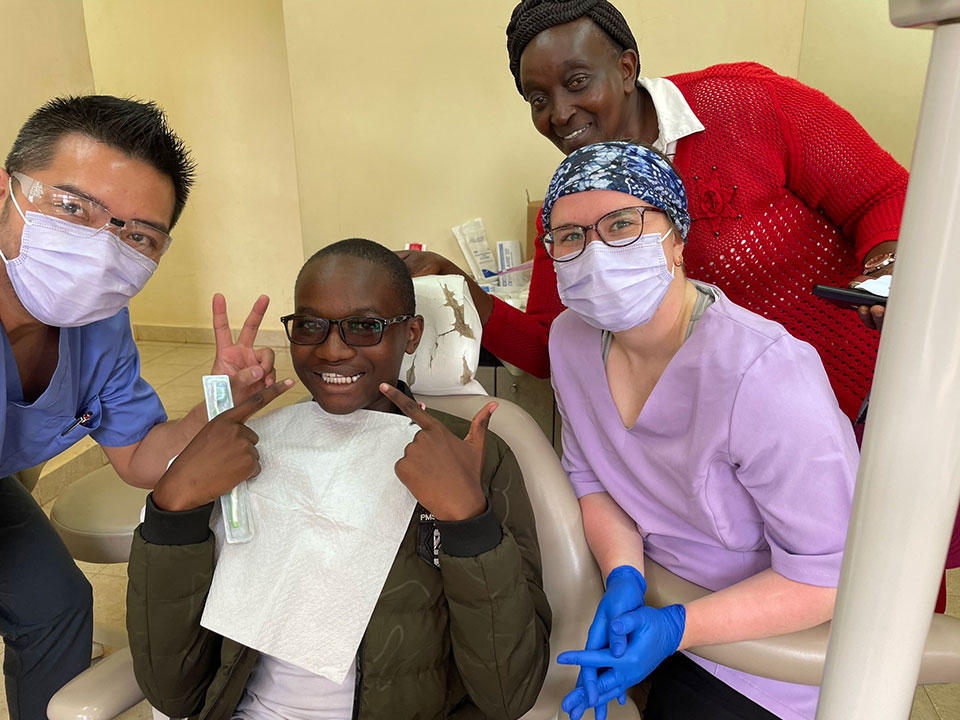 A group of healthcare professionals posing for a photo in a dental office, with one individual seated in the dentist's chair.