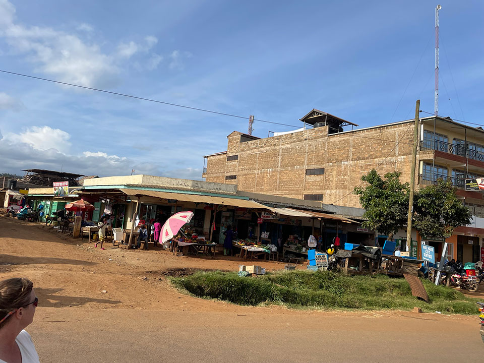 The image depicts a street scene in an urban area with buildings, shops, and people.