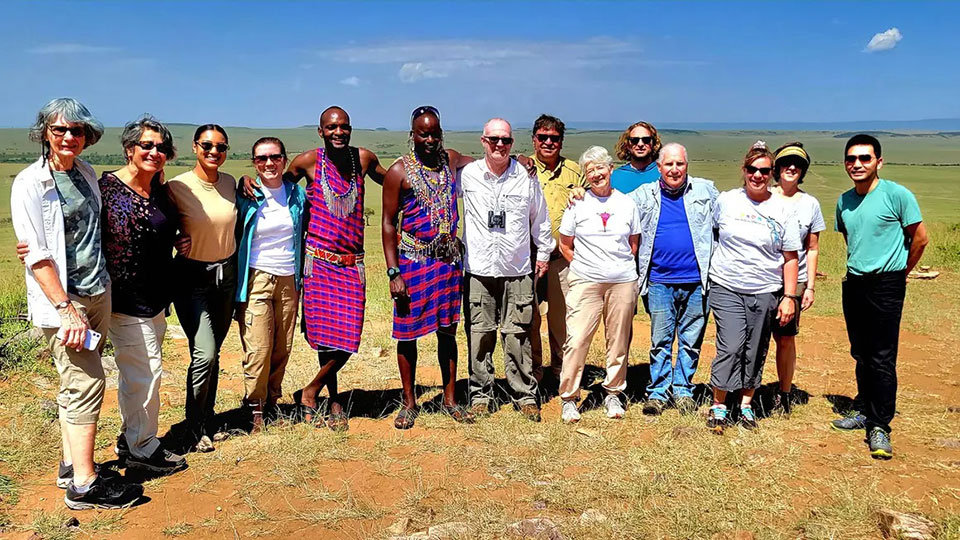 Group of people posing for a photo on a dirt road, with a clear sky in the background.