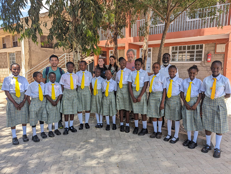 A group of young individuals wearing school uniforms, posing for a photo in front of a building.