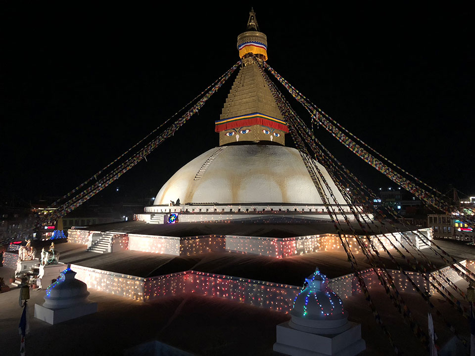 This image captures the majestic Lotus Temple, a Bahá' House of Worship located in New Delhi, India. The temple is illuminated at night and stands out against the dark sky.