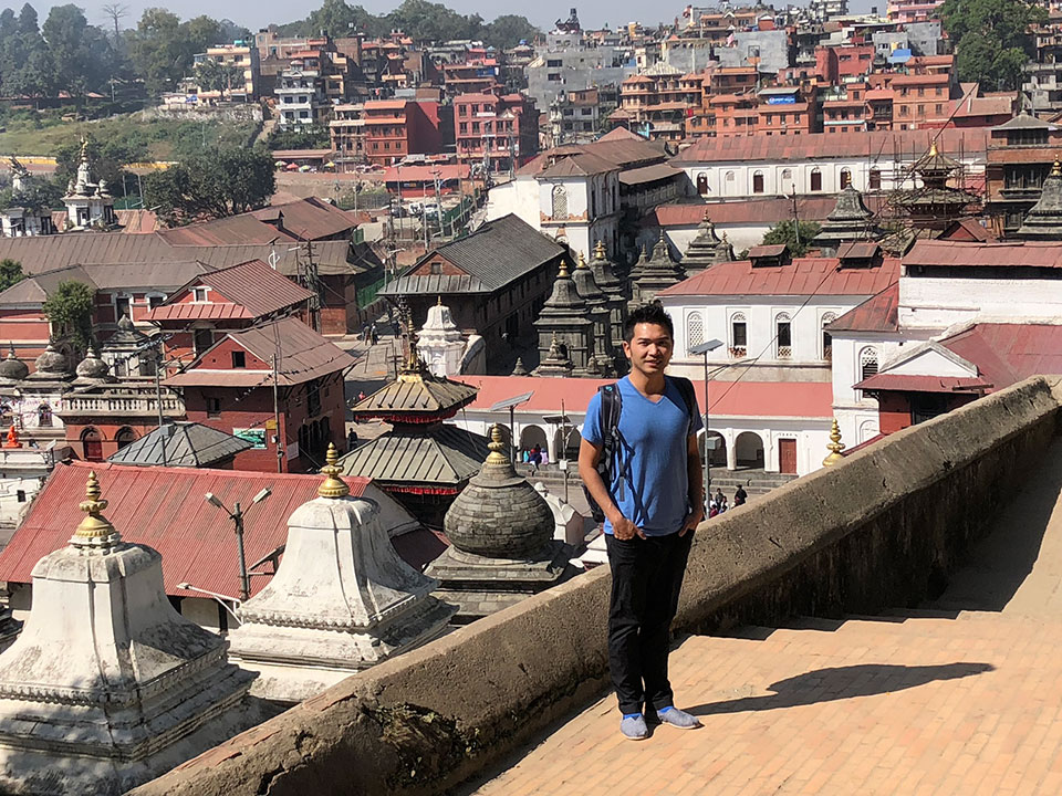 A person standing on a high vantage point overlooking an ancient city with colorful buildings and temples.