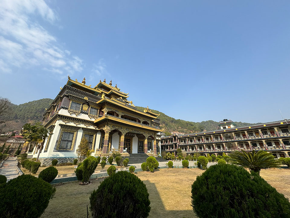 The image shows a traditional-style building with multiple levels and intricate architectural details, set against a clear sky.