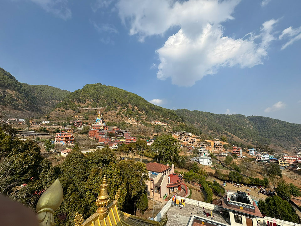 The image depicts a scenic mountainous landscape with a town or village nestled among the hills, featuring traditional architecture and lush greenery.