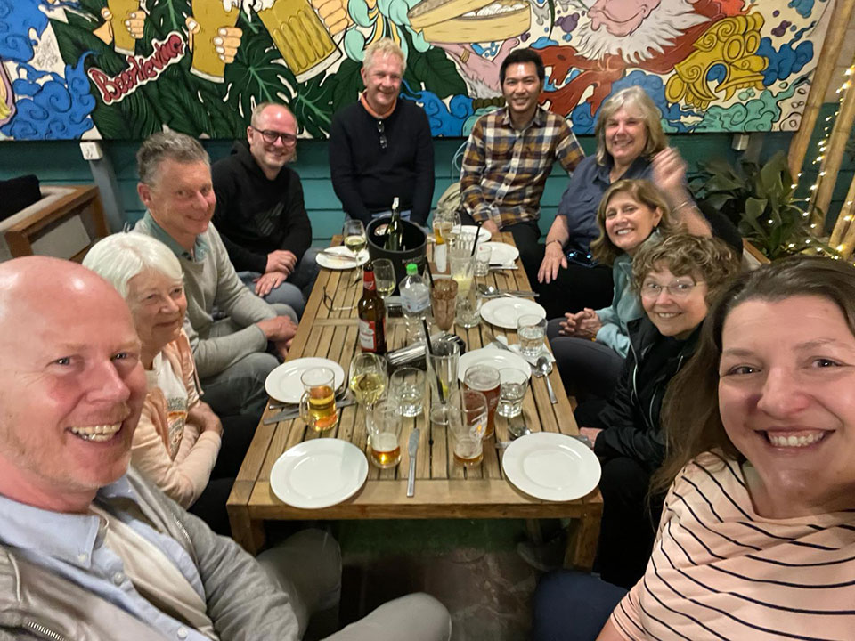 A group of people gathered around a dining table in a restaurant, posing for a photograph.
