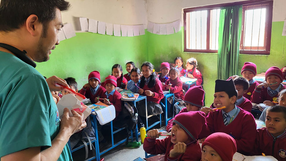 A man, presumably a teacher, in a classroom setting is giving a lecture to students who are engaged in an activity.