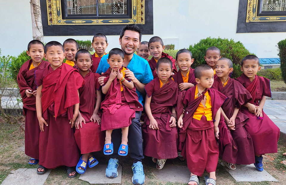 A group of young boys in traditional Buddhist attire, posing for a photo with an adult male.