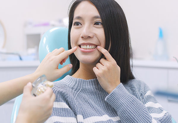 A woman receiving dental care in a professional setting, with visible smiles and dental tools.