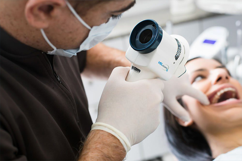 A dental professional using a high-tech device to examine a patient s mouth.