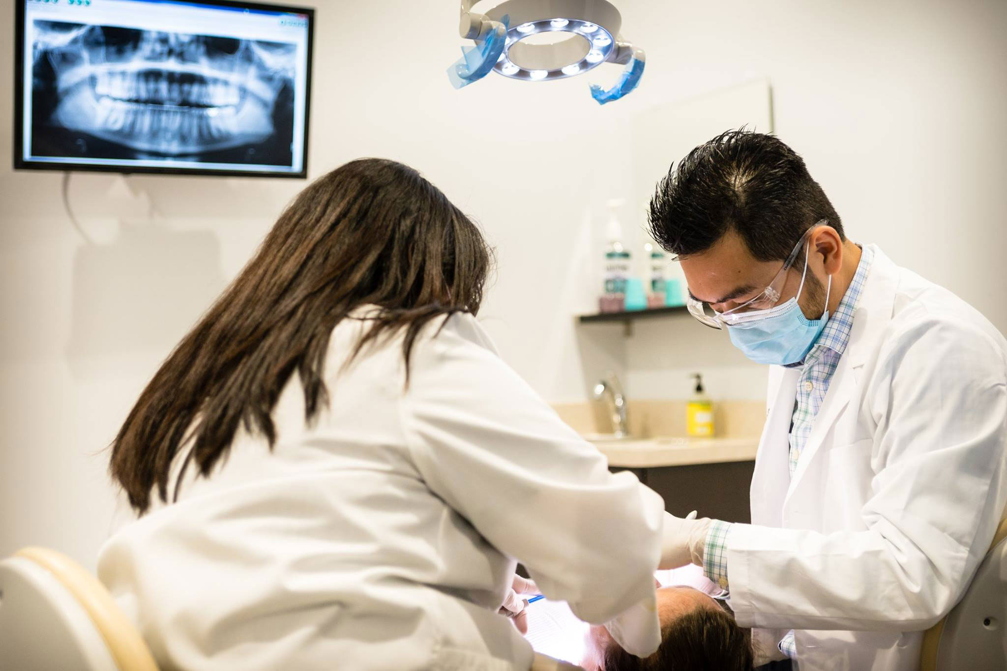 Dental professionals in a clinic, with one person seated at a desk and another standing behind them.