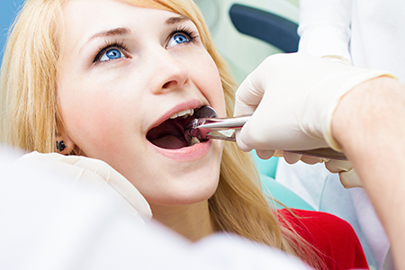 A woman receiving dental care with a dentist performing the procedure.