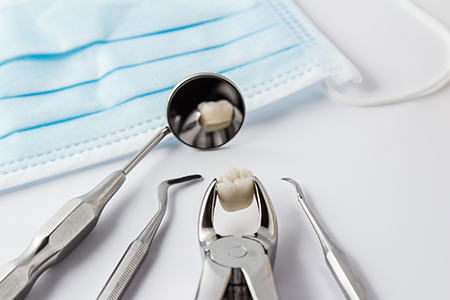 Dental tools with a toothbrush, set against a blue surgical mask on a white background.