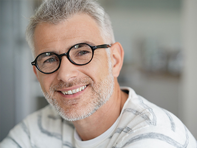 A man with glasses and a beard is smiling at the camera.