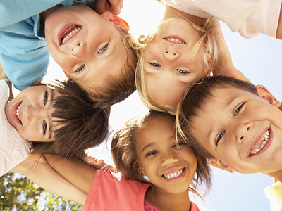 A group of children joyfully posing for a photo, displaying a range of expressions and ages.