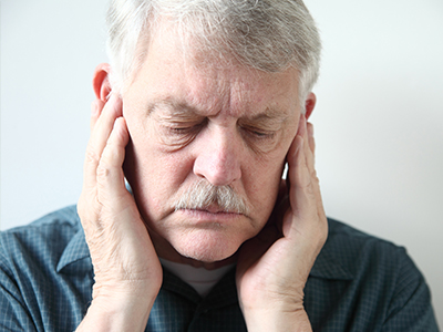 Man with hand on face, appearing to be in pain or discomfort.